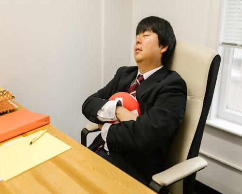 A person resting their eyes by leaning back in an office chair