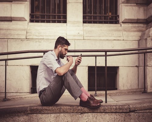 Person typing on a smartphone while sitting on a sofa