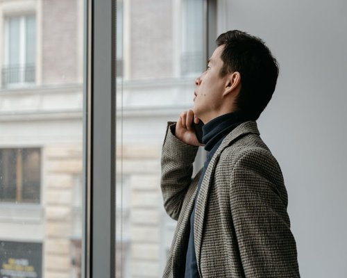 A person looking out of a window thoughtfully, taking a break from work